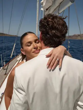 A couple is hugging on a sailboat.
