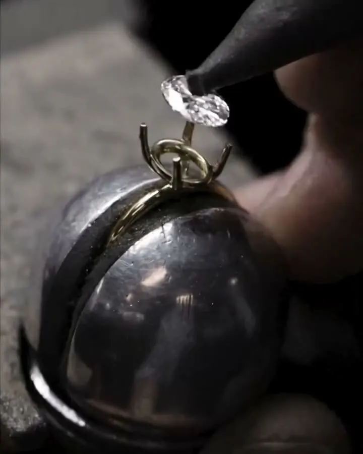 An oval stone is set into the prongs of a gold setting.