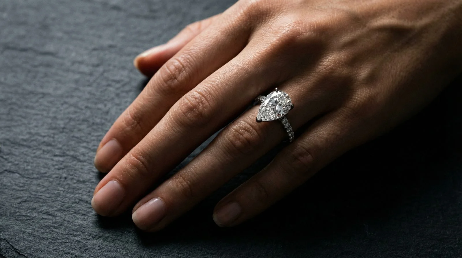 Pear-Schliff Tropfenschliff Verlobungsring am Finger – Moissanit auf dunklem Schiefer