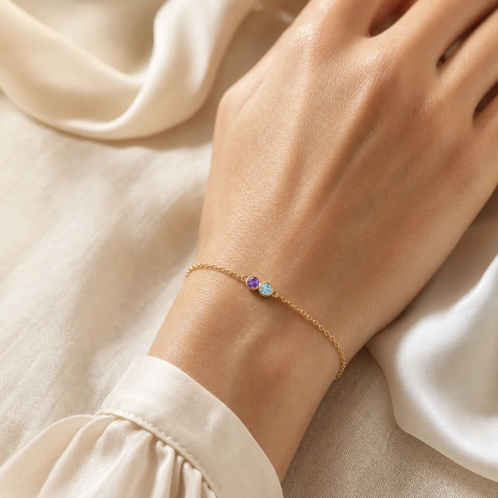Liora Duo Geburtsstein-Armband mit Amethyst und Aquamarin am Handgelenk auf heller Seide
